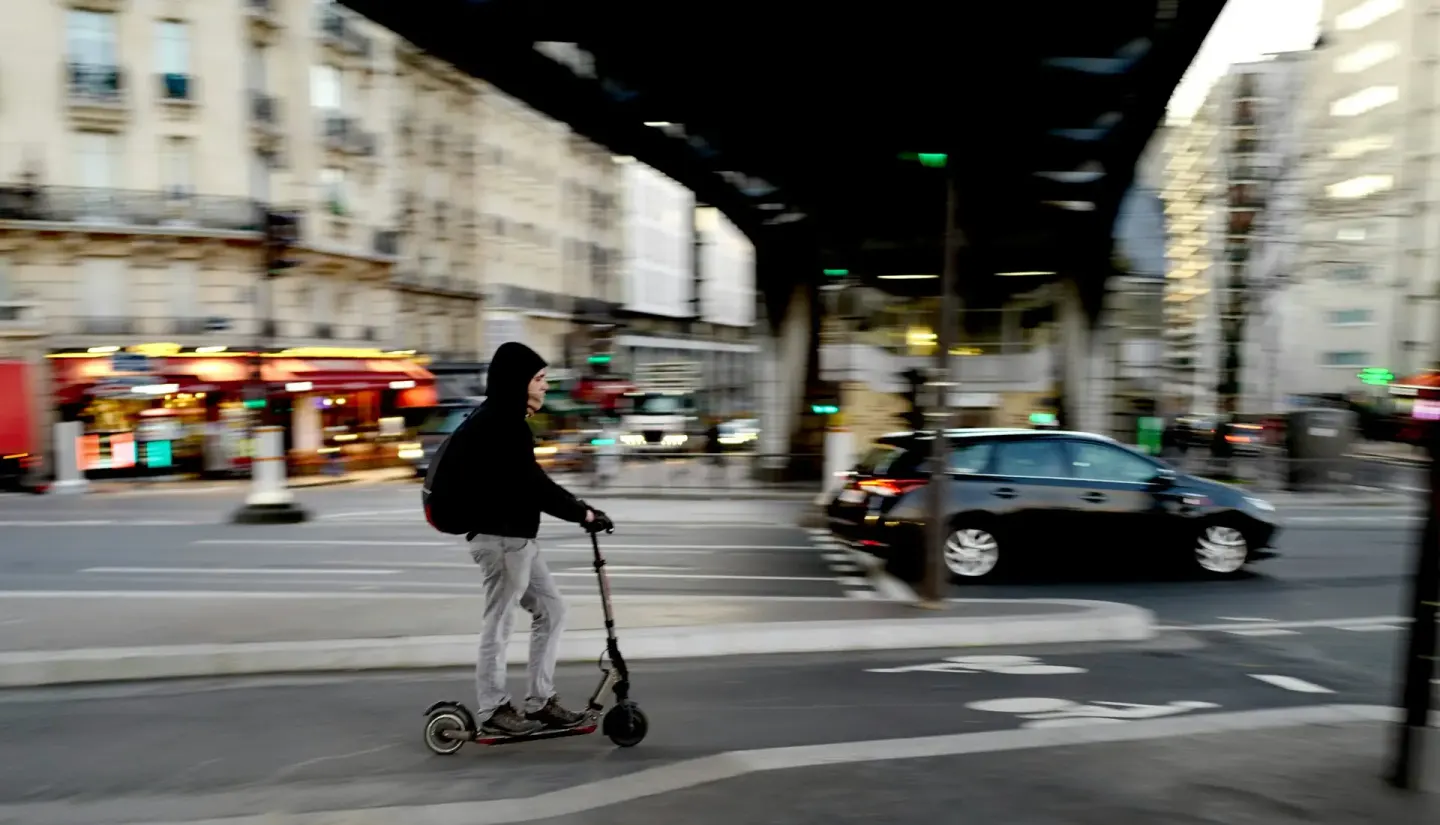 Usager en trottinette électrique traversant une rue de Paris